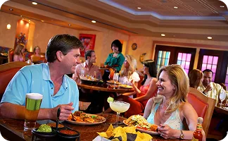 A couple is sitting at a table in a restaurant, eating and talking.