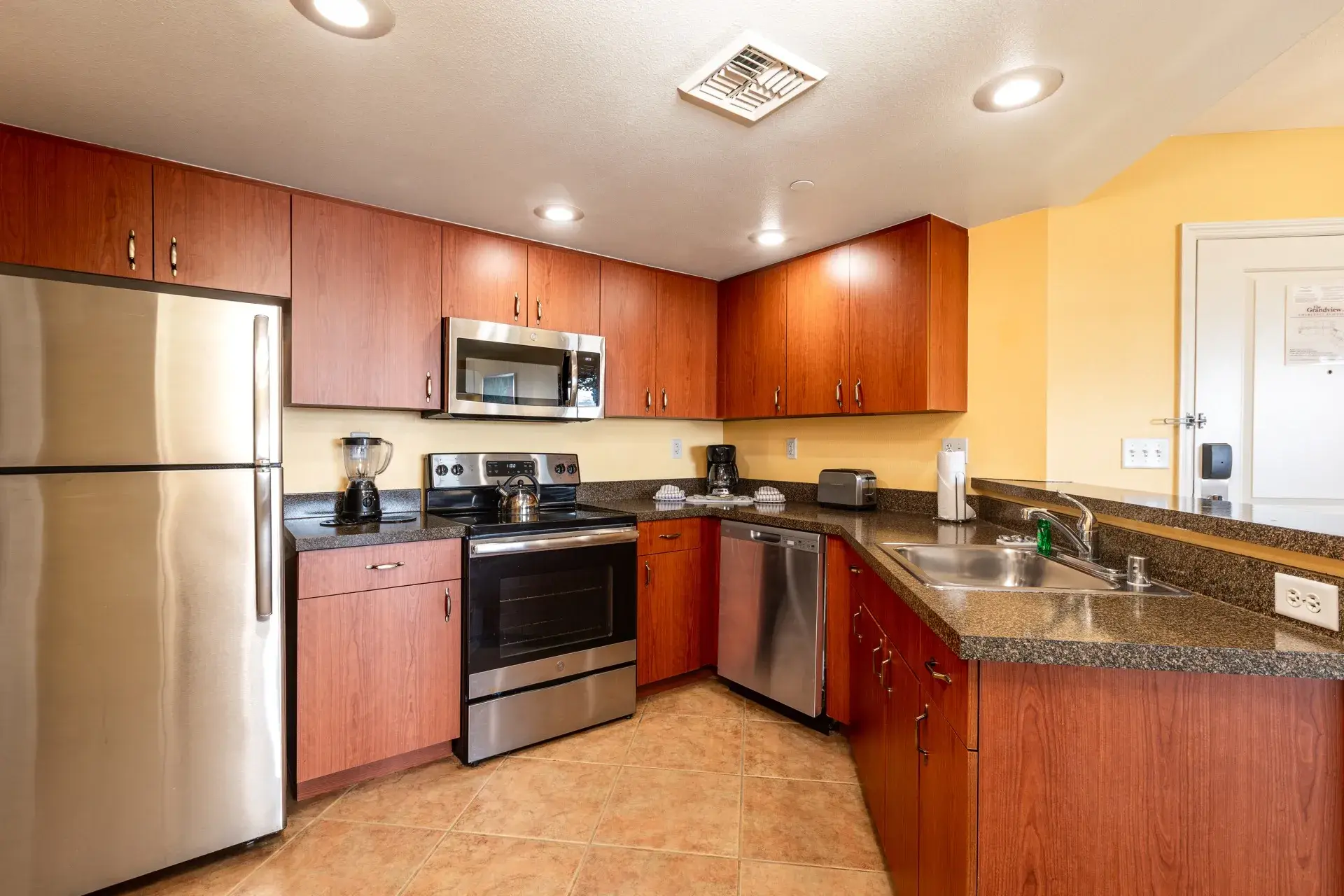 A kitchen with full-size refrigerator, stove, microwave oven, and dishwasher